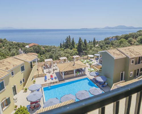 A balcony view of an outdoor swimming pool alongside resort condos.