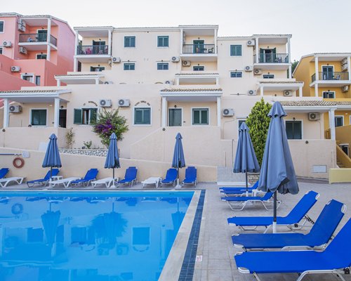 An outdoor swimming with chaise lounge chairs alongside resort condos.