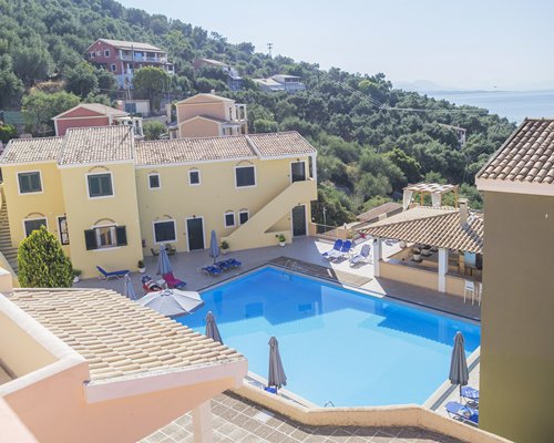 An outdoor swimming pool with chaise lounge chairs alongside multiple story condos.