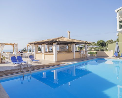An outdoor swimming pool with chaise lounge chairs and a poolside bar.