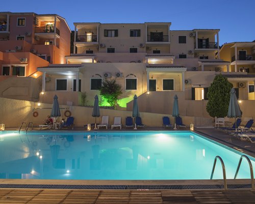 An outdoor swimming pool with chaise lounge chairs alongside resort condos.