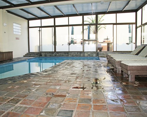 An indoor swimming pool with chaise lounge chairs.