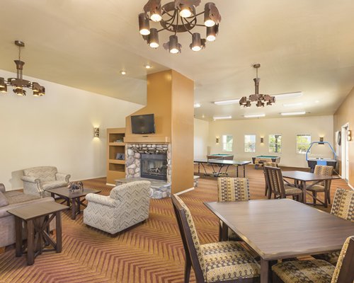A well furnished recreation room with a fireplace and pool tables.