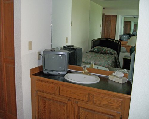 A bedroom with a sink and television.