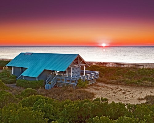 View of beach cabanas alongside ocean at dusk.