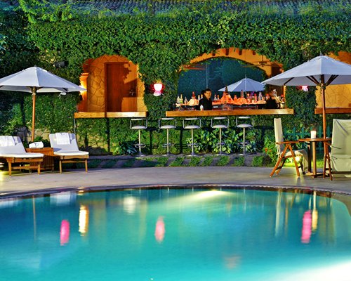 An outdoor swimming pool with chaise lounge chairs and patio chair alongside a bar.