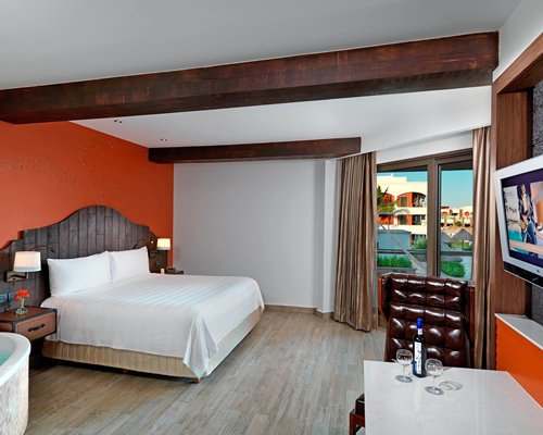 A well furnished bedroom with king bed television and an outside view.