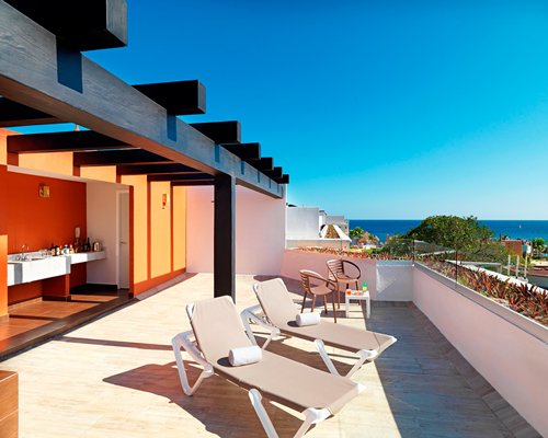 Balcony with chaise lounge chairs patio furniture and ocean view.