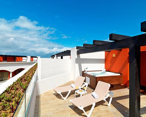 An exterior view of chaise lounge chairs alongside a hot tub.