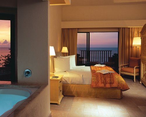 A well furnished bedroom with a king bed bathtub and ocean view.