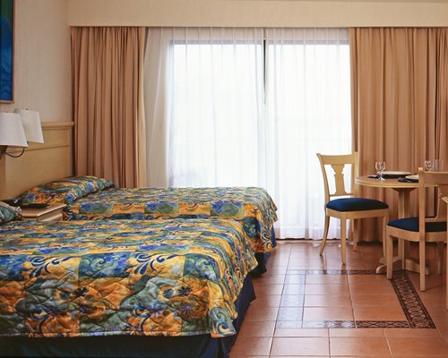 A well furnished bedroom with two beds and dining table.
