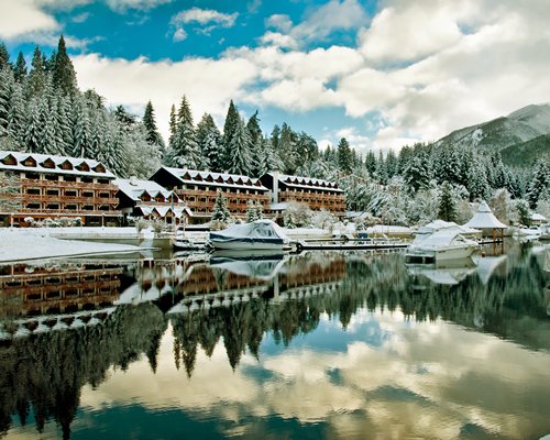 A lake view of the resort condos alongside pine trees covered in snow.