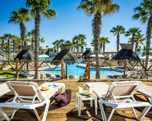 BEACH VIEW OF THATCHED SUNSHADES AND CHAISE LOUNGE CHAIRS.