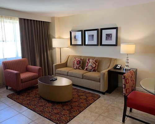 An open plan dining living area with a television and a glass top table.