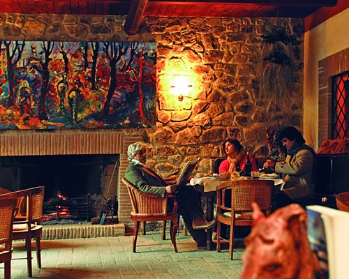 A family in an indoor restaurant with a fire in the stone fireplace.