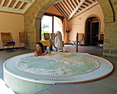 A Woman at an indoor hot tub with chaise lounge chairs.