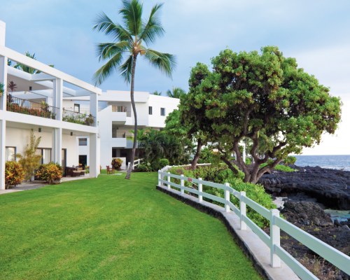EXTERIOR VIEW OF MULTI STORY RESORT UNITS WITH PALM TREES.