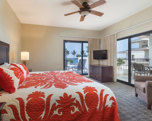 A WELL FURNISHED BEDROOM WITH TELEVISION ALONGSIDE PATIO FURNITURE AND CHAISE LOUNGE CHAIRS IN THE PATIO.