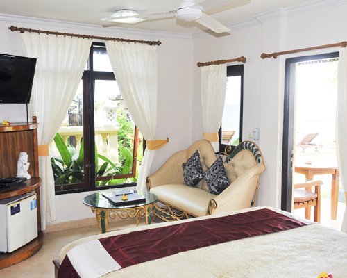 A well furnished bedroom with a queen bed television and patio.