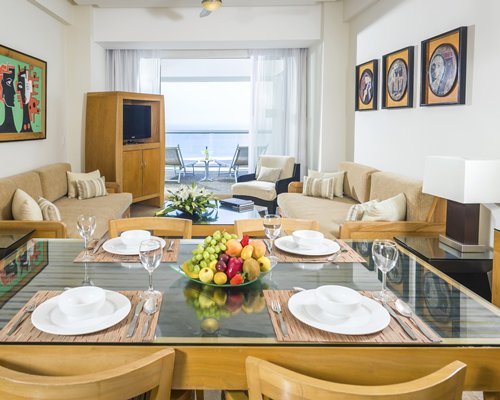 A well furnished living and dining area with a television and a balcony with patio.