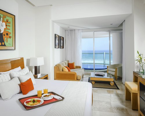 A well furnished bedroom with a king bed sofa and the ocean view.