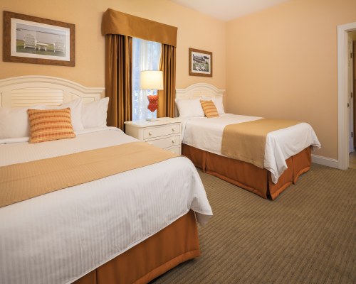 A BEDROOM WITH TWO LARGE BEDS AND A WINDOW.