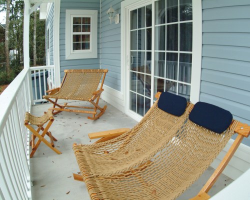 AN OUTDOOR PORCH WITH SEATING OFF LIVING AREA.