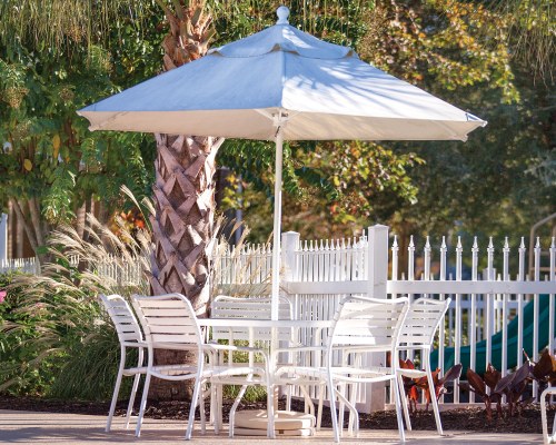 AN OUTDOOR TABLE AND CHAIRS WITH AN UMBRELLA.