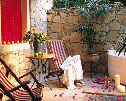 Outdoor hot tub with chaise lounge chairs candles and landscaping.