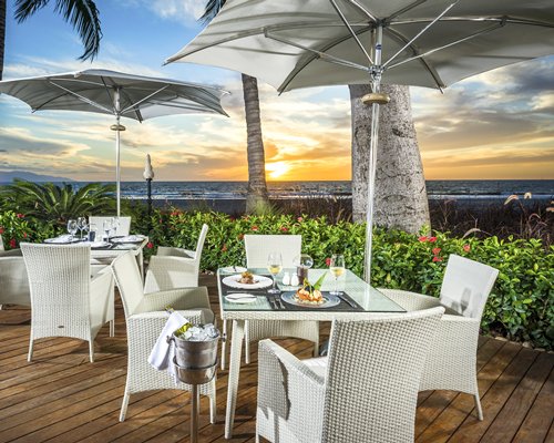 An outdoor fine dining restaurant alongside the beach at dusk.
