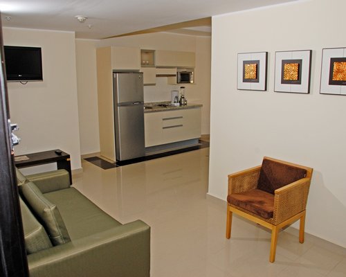 A well furnished living room with open plan kitchen and television.