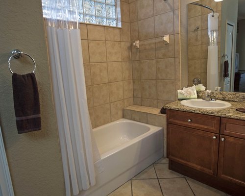 A bathroom with a bathtub and single sink vanity.