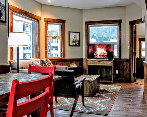 A well furnished living room with fire in the fireplace and dining area.