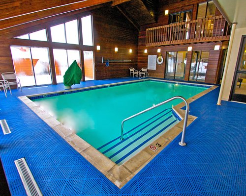 An indoor swimming pool with patio furniture and an outside view.