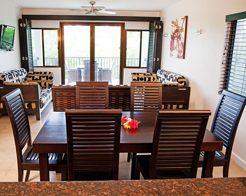 A well furnished living room with dining area television balcony and outdoor dining.