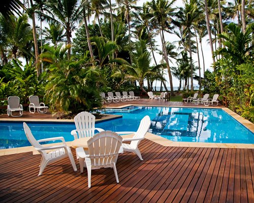 An outdoor swimming pool with patio furniture and chaise lounge chairs.