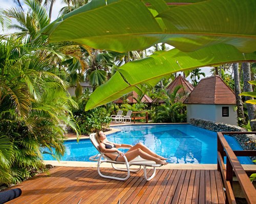 A woman relaxing in a chaise lounge chair alongside a swimming pool.