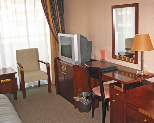 A well furnished room with a television and dresser.