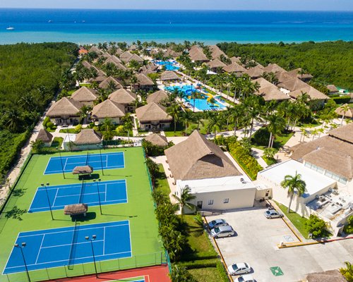 An aerial view of the resort with tennis courts pools and ocean.