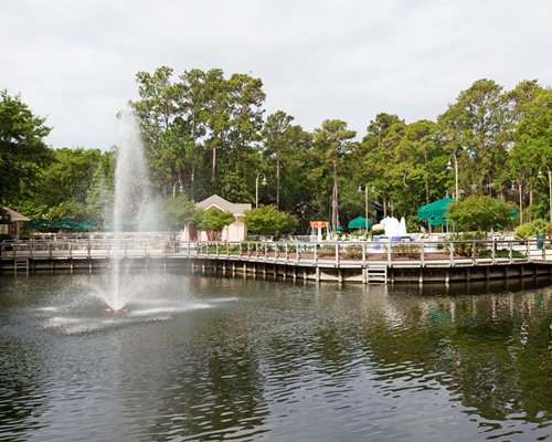 A fountain in the waterfront alongside the resort units surrounded by trees.