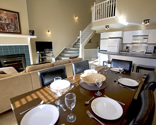 A well furnished living room with television fireplace open plan kitchen dining area and a stairway.