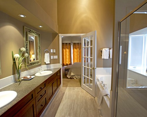 A bathroom with bathtub shower and double sink vanity.