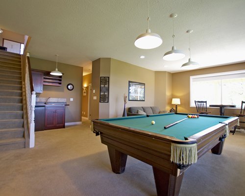 Indoor recreation room with pool table lounge area and a stairway.