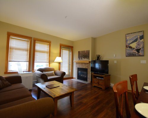 A well furnished living room with a television fireplace dining area and outside view.