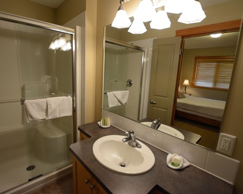 A bathroom with a shower stall closed sink vanity and view of the bedroom.