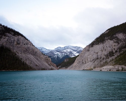 View of the water alongside mountains covered with snow.