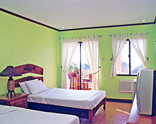 A well furnished bedroom with two twin beds television and balcony.