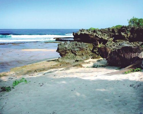 View of the beach and ocean with rocks.