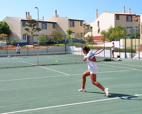 View of ladies playing tennis in an outdoor court alongside the resort.
