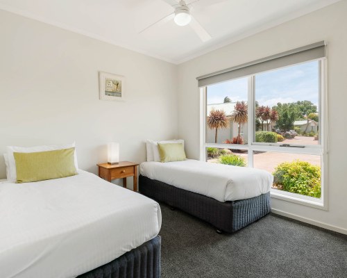 A WELL FURNISHED BEDROOM WITH LAMPS AND OUTSIDE VIEW.